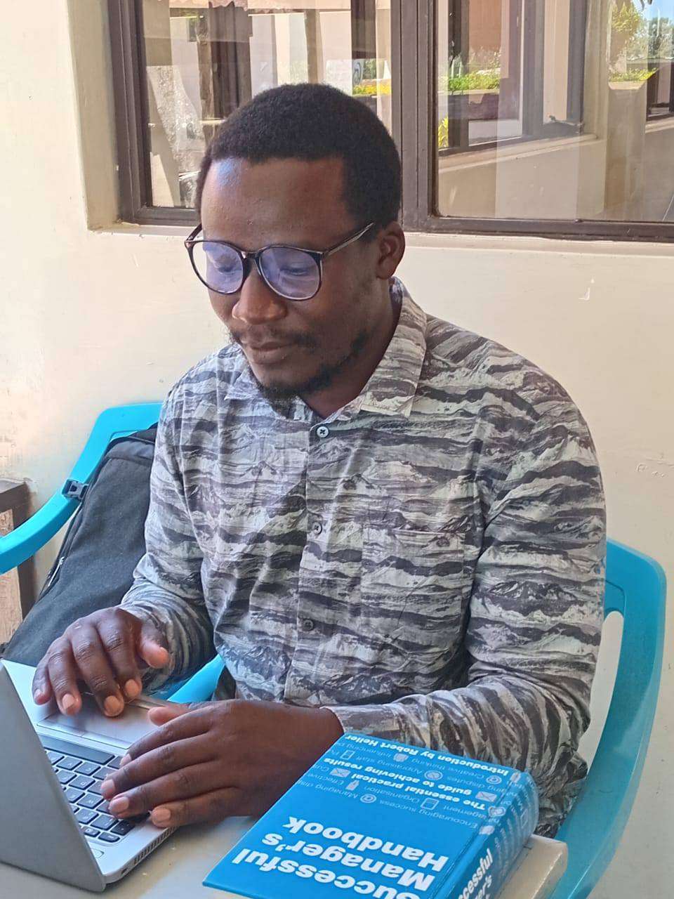 founder of bleeding ink scribes publishers limited Sir Banface working in his laptop